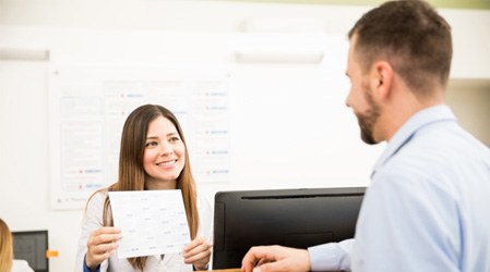 a dental assistant helping a patient pick an appointment date