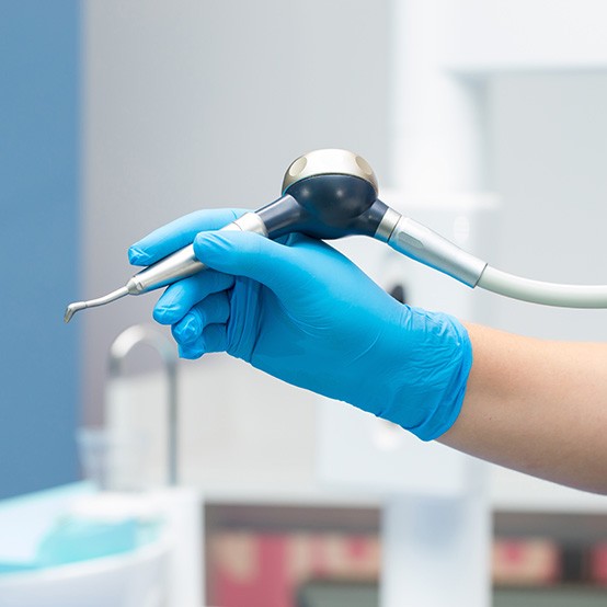 Dentist holding airflow tool in gloved hand