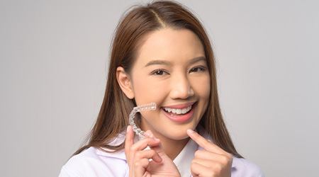 Woman smiling while pointing to clear aligner