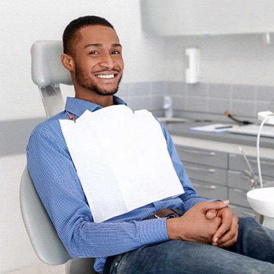 Man sitting in dental chair with hands folded