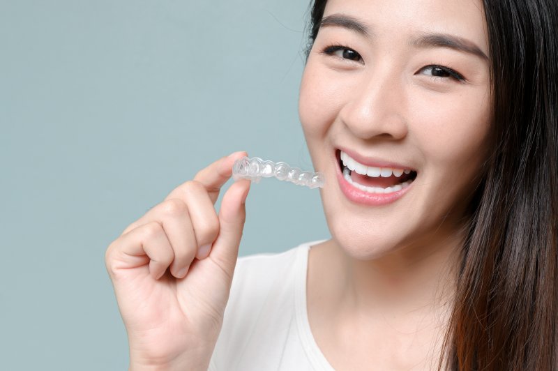 person smiling and holding clear aligners tray