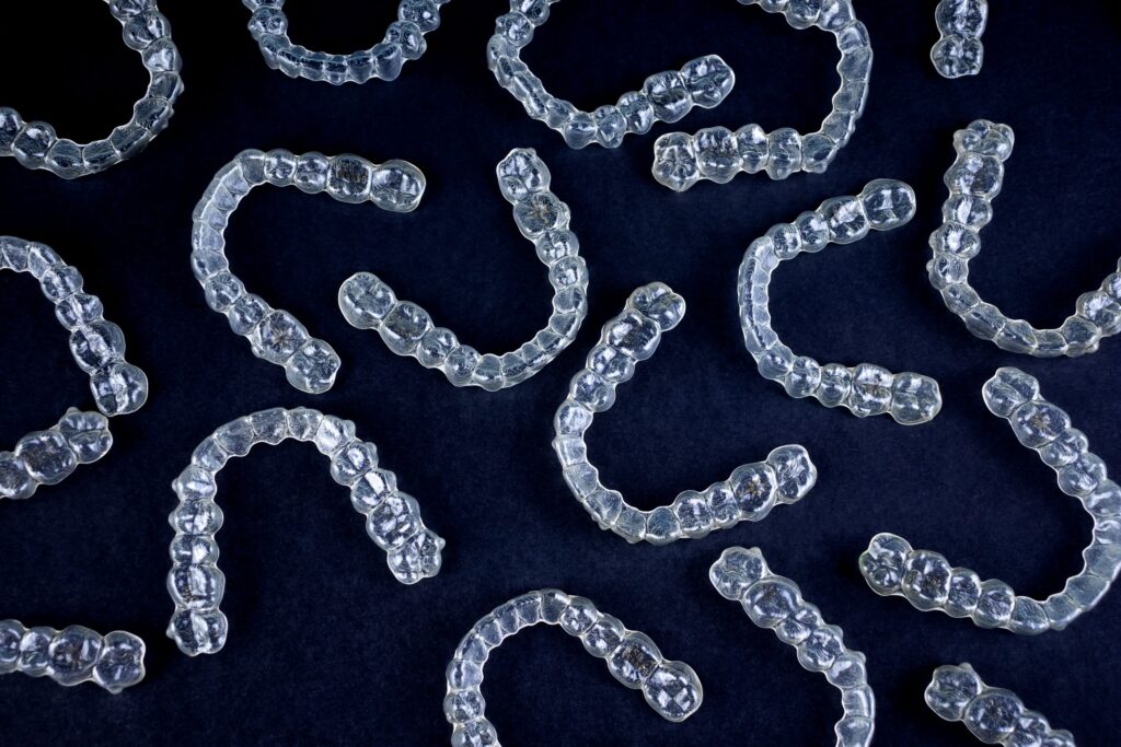 Bird's eye view of several clear aligners on a black background